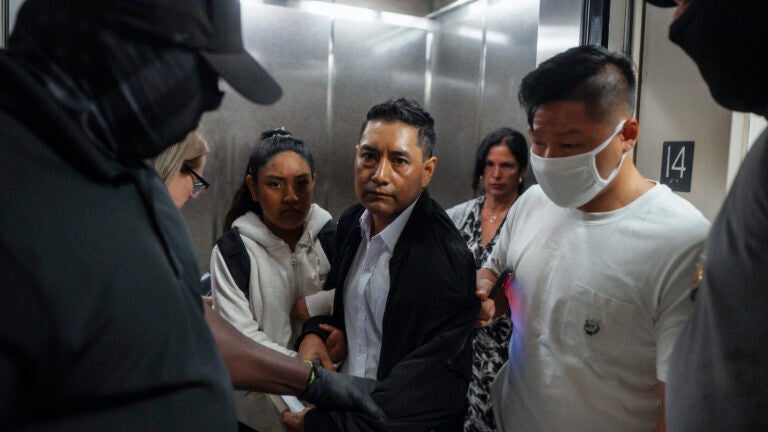 Immigration and Customs Enforcement agents pull a man out of an elevator as he and his daughter attempt to leave following a hearing in immigration court.