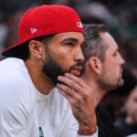 Boston Celtics forward Jayson Tatum, who is recovering from surgery, watches during the first half of a preseason NBA basketball game against the Toronto Raptors, Wednesday, Oct. 15, 2025, in Boston.