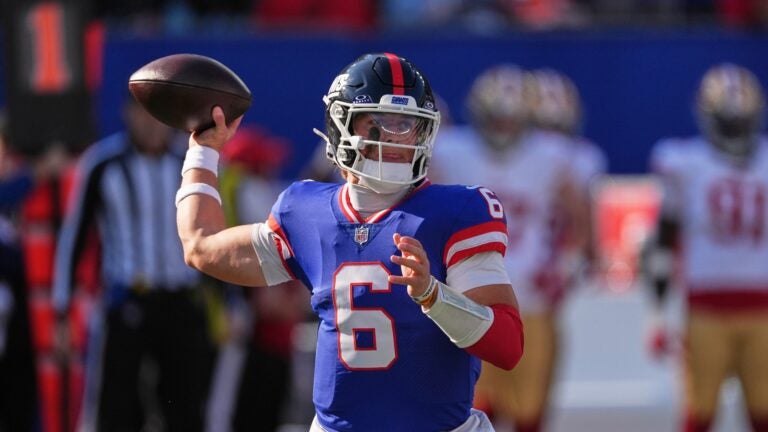 Giants quarterback Jaxson Dart readies to throw a pass with a football in hand and his arm bent back.